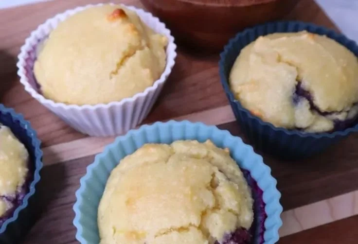 Almond flour lemon blueberry muffins fresh out of the oven, topped with blueberries.