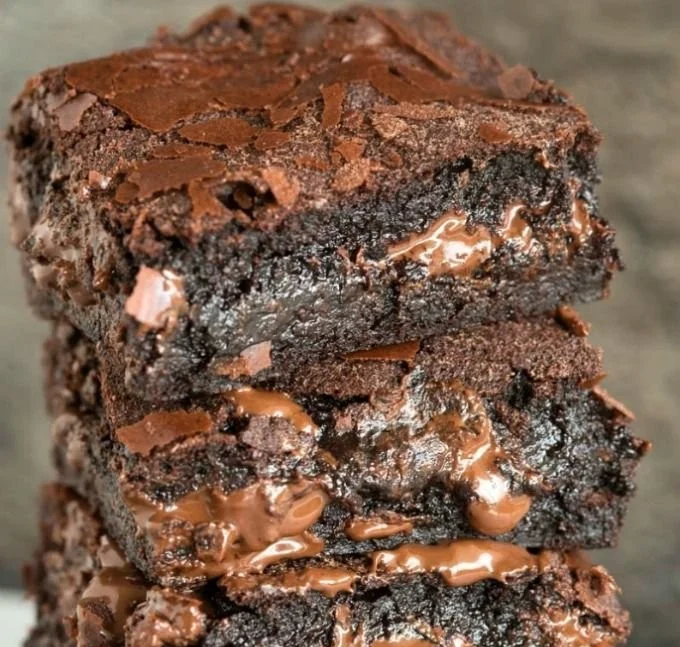 Decadent calorie fudge brownies on a cooling rack topped with chocolate drizzle.