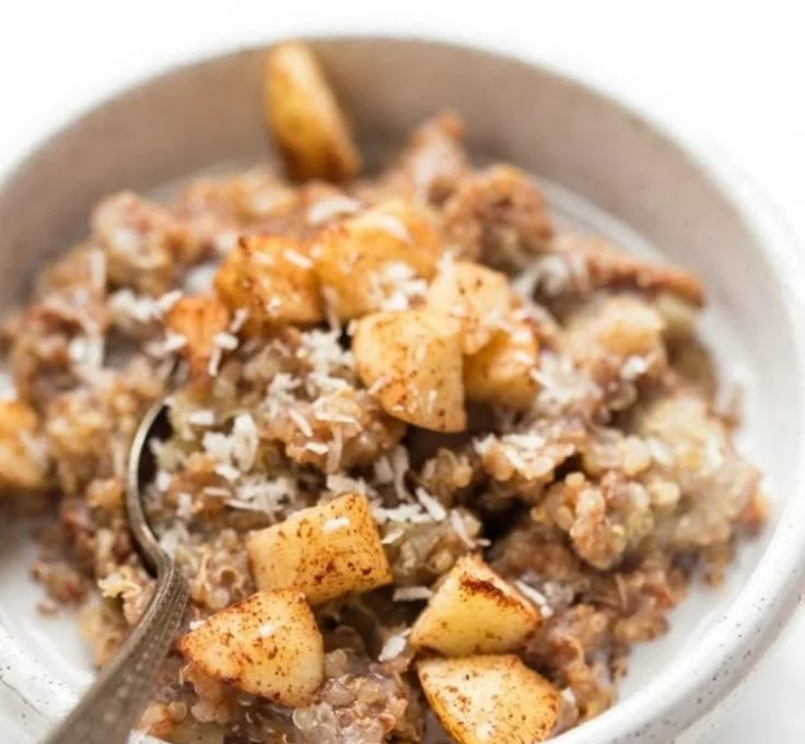 Delicious cinnamon apple quinoa breakfast bowl topped with nuts and fruits.
