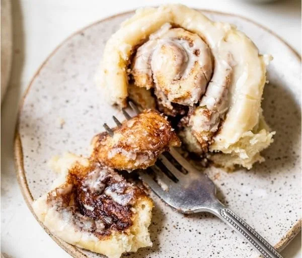 Delicious homemade vegan cinnamon rolls with creamy frosting on a plate.