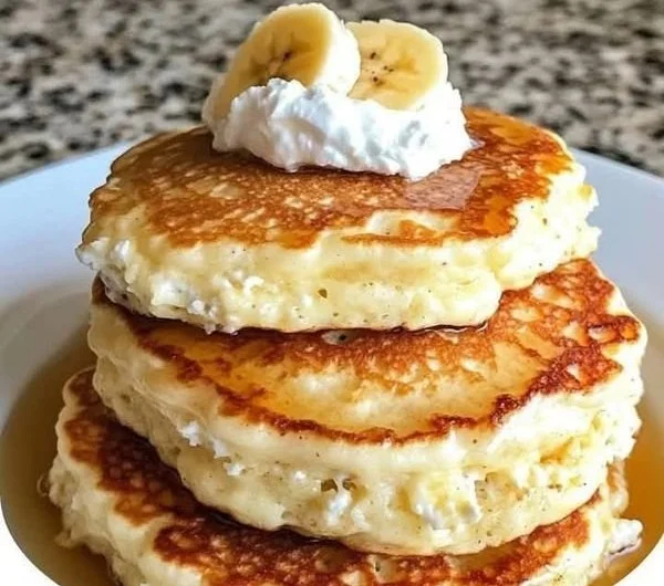 Fluffy banana pancakes topped with syrup and sliced bananas