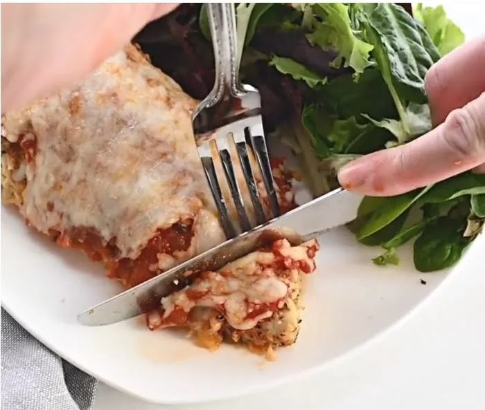 Keto Chicken Parmesan dish garnished with fresh basil and served with marinara sauce